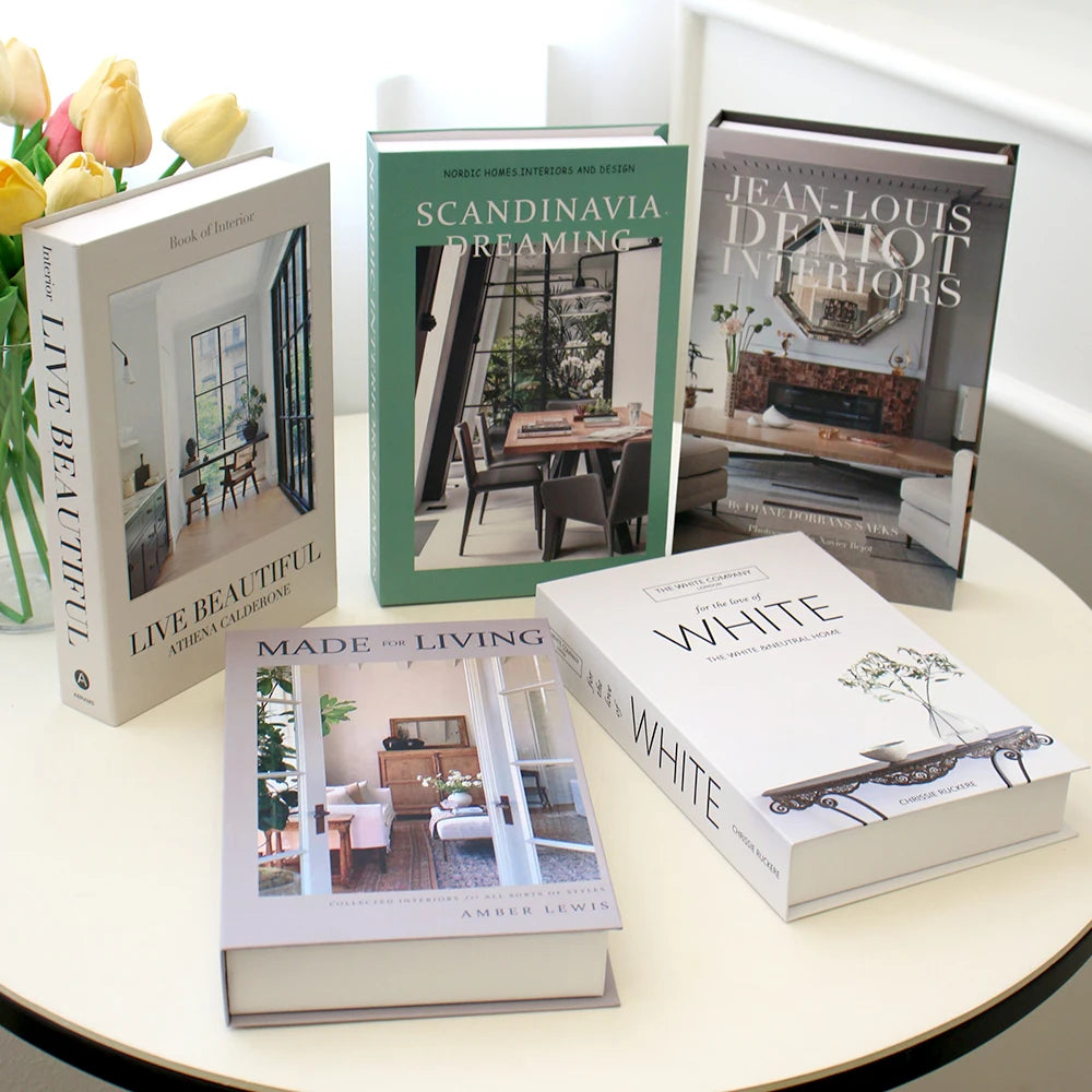 Collection of interior design books on a table with flowers in the background