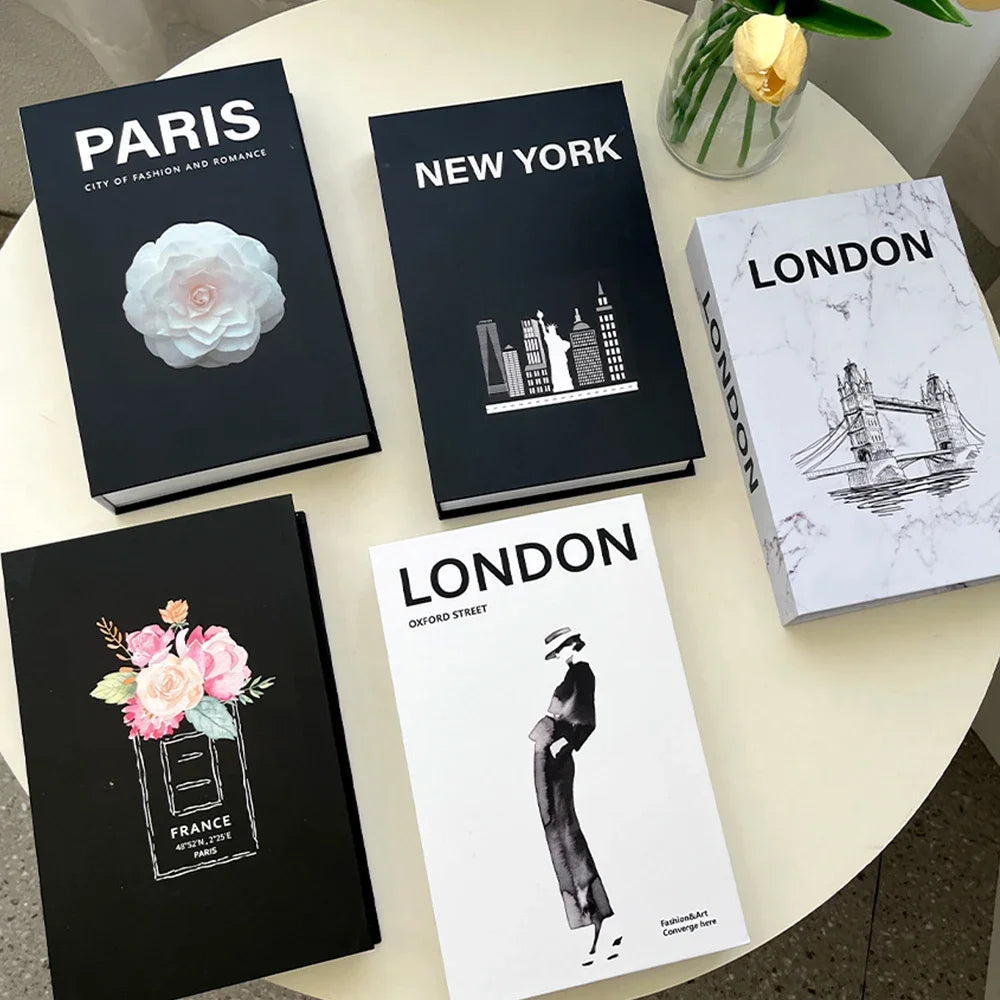 Books titled 'Paris', 'New York', and 'London' on a table with decorative elements.