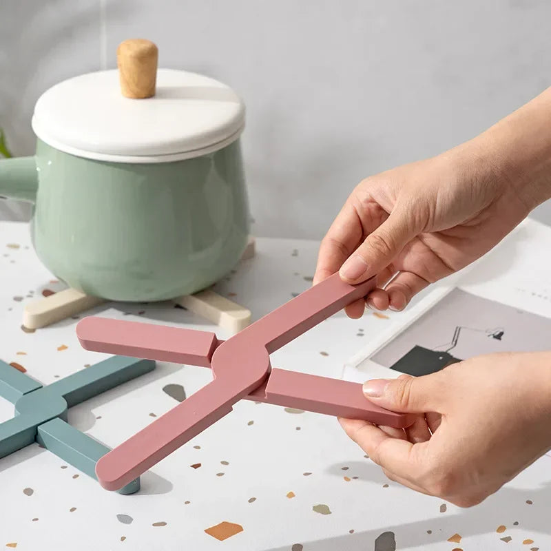 Person holding a pink kitchen tool with a green pot in the background