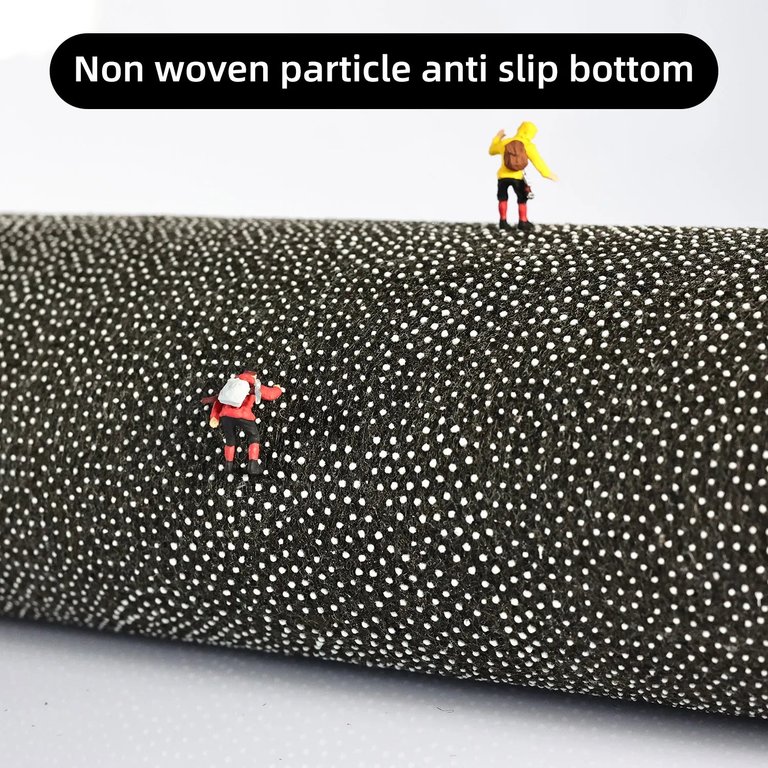 Roll of black fabric with white dots and toy figures on top, labeled 'Non woven particle anti slip bottom'.
