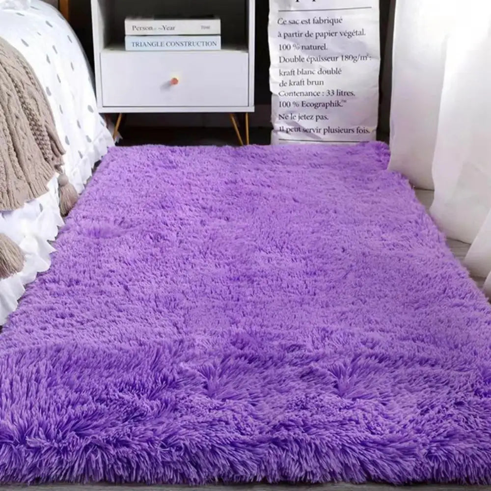 Purple shaggy rug on a white surface with a textured wall and books in the background.