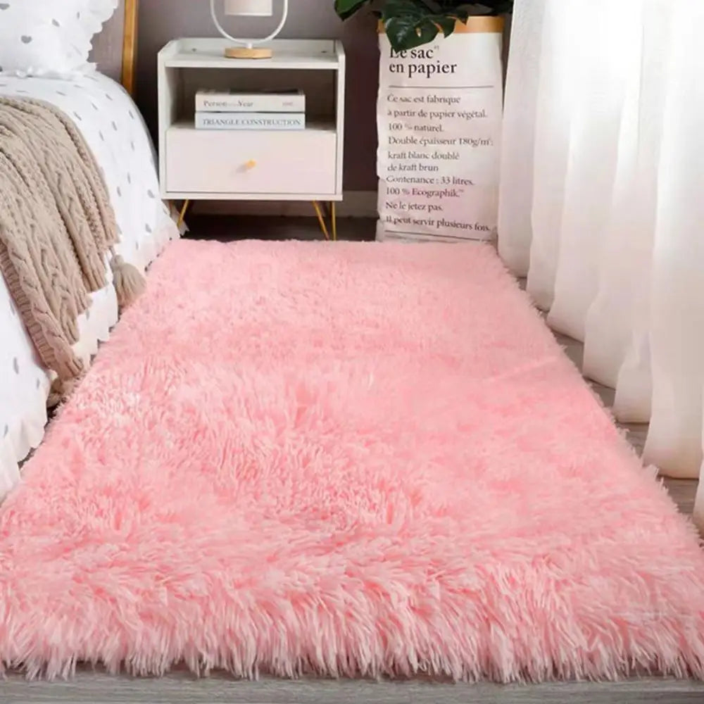 Pink fluffy rug on a wooden floor with a white nightstand and books in the background.