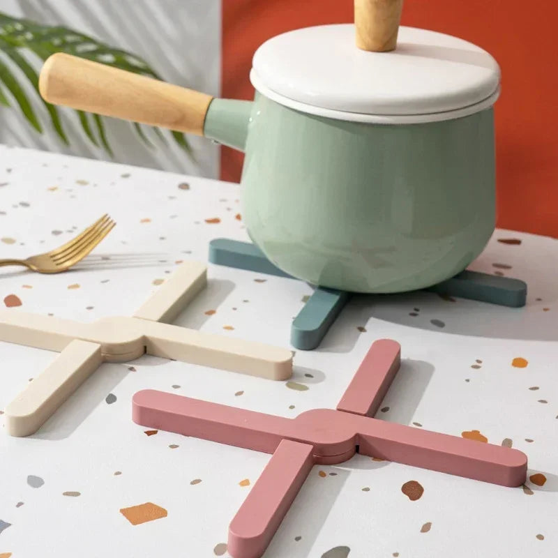 Children's toy kitchen set with a green pot and pink spatula on a patterned tablecloth.