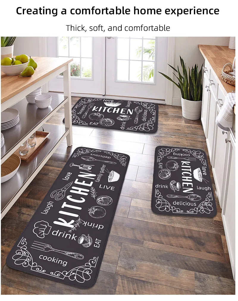Black kitchen mats with white text on a wooden floor in a kitchen setting.