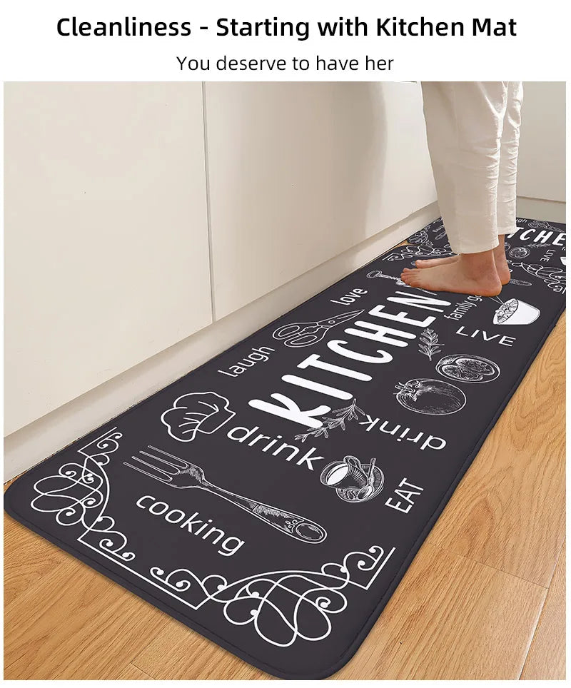 Black kitchen mat with white text and graphics on a wooden floor.