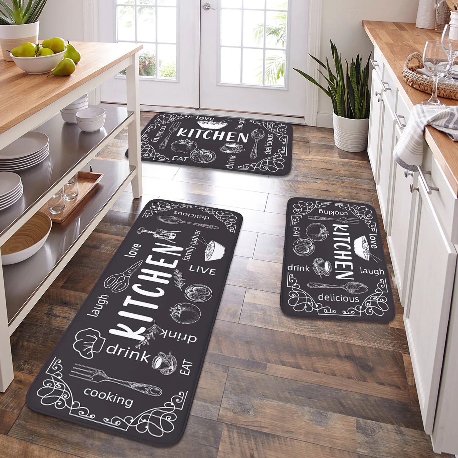 Three black kitchen mats with white text and graphics on a wooden floor.