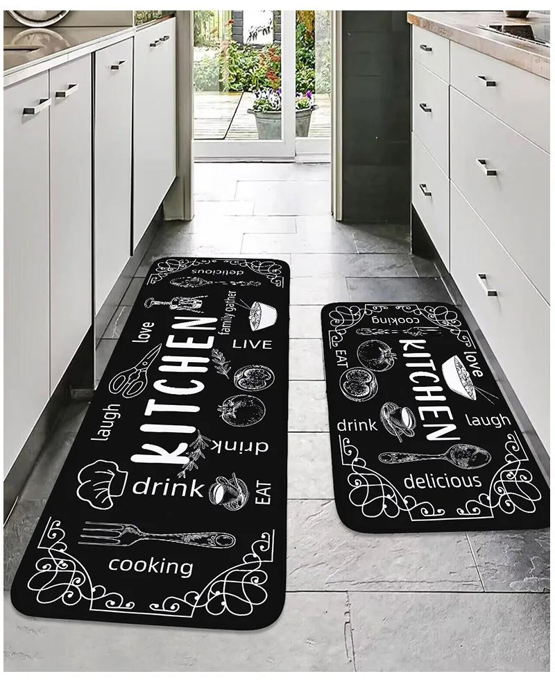 Two black kitchen mats with white text and graphics on a gray floor.