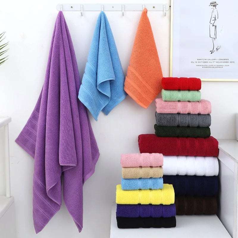 Colorful towels hanging and stacked on a white surface with a minimal background.
