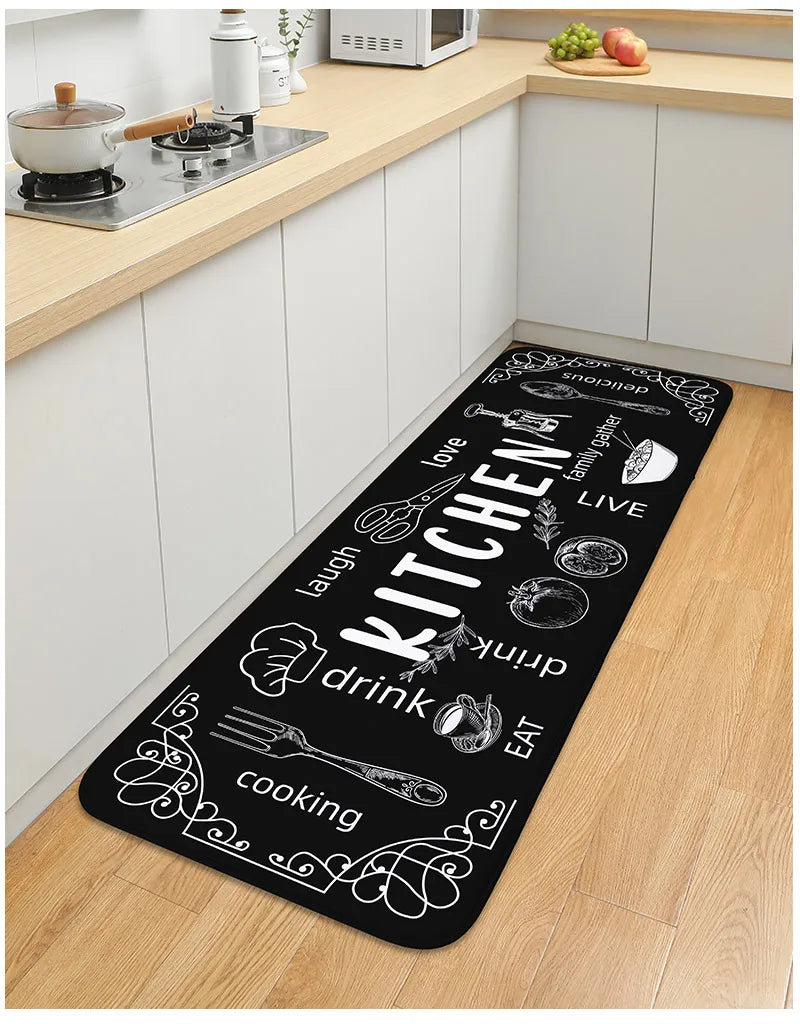 Black kitchen mat with white text and graphics on a wooden floor in a kitchen setting.