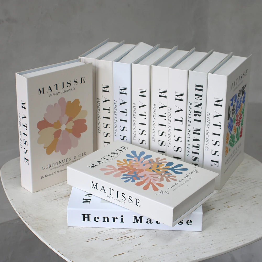 Collection of books titled 'Matisse' on a round wooden table with a gray background