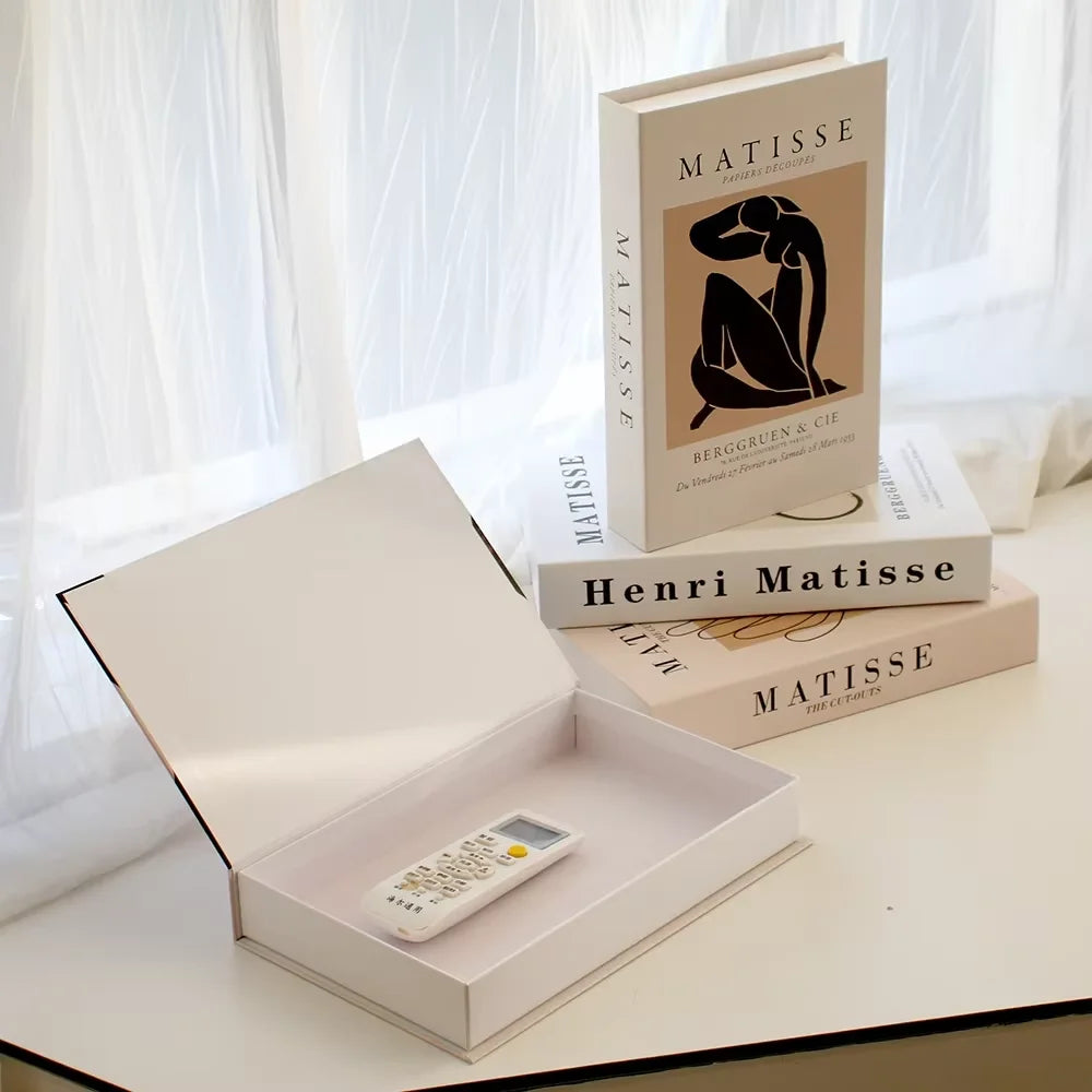 Open box with a remote control on a surface with Matisse books in the background