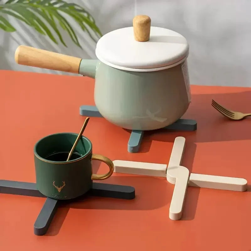 Small green pot with wooden handle and white lid on a red surface, accompanied by a matching mug and wooden sticks.
