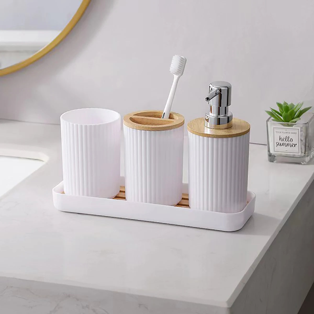 Bathroom counter with white and wooden toothbrush holder, cup, and soap dispenser.