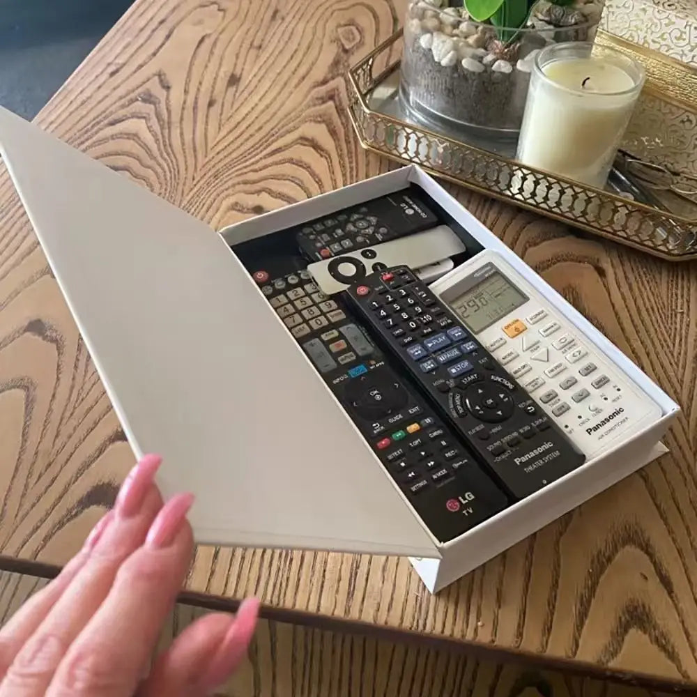 Box containing various remote controls on a wooden table