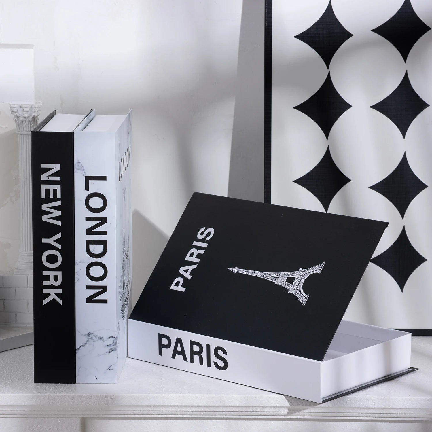 Decorative bookends with 'New York' and 'London' on black and white books, and a box labeled 'Paris' with the Eiffel Tower on a decorative wall background.